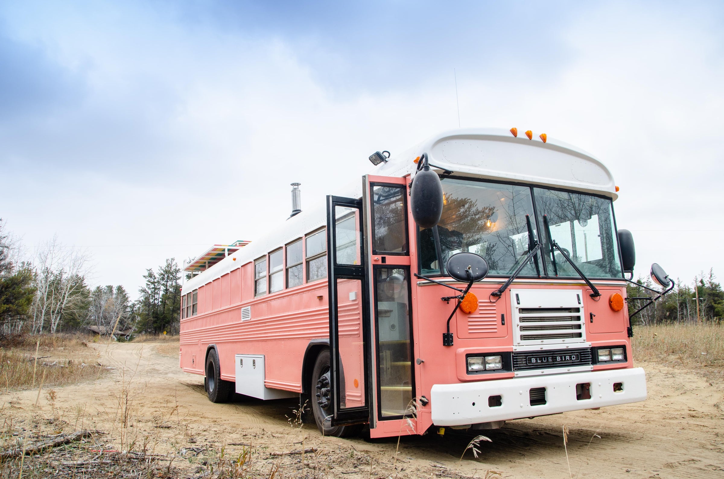 Pink school bus conversion with a rainbow deck