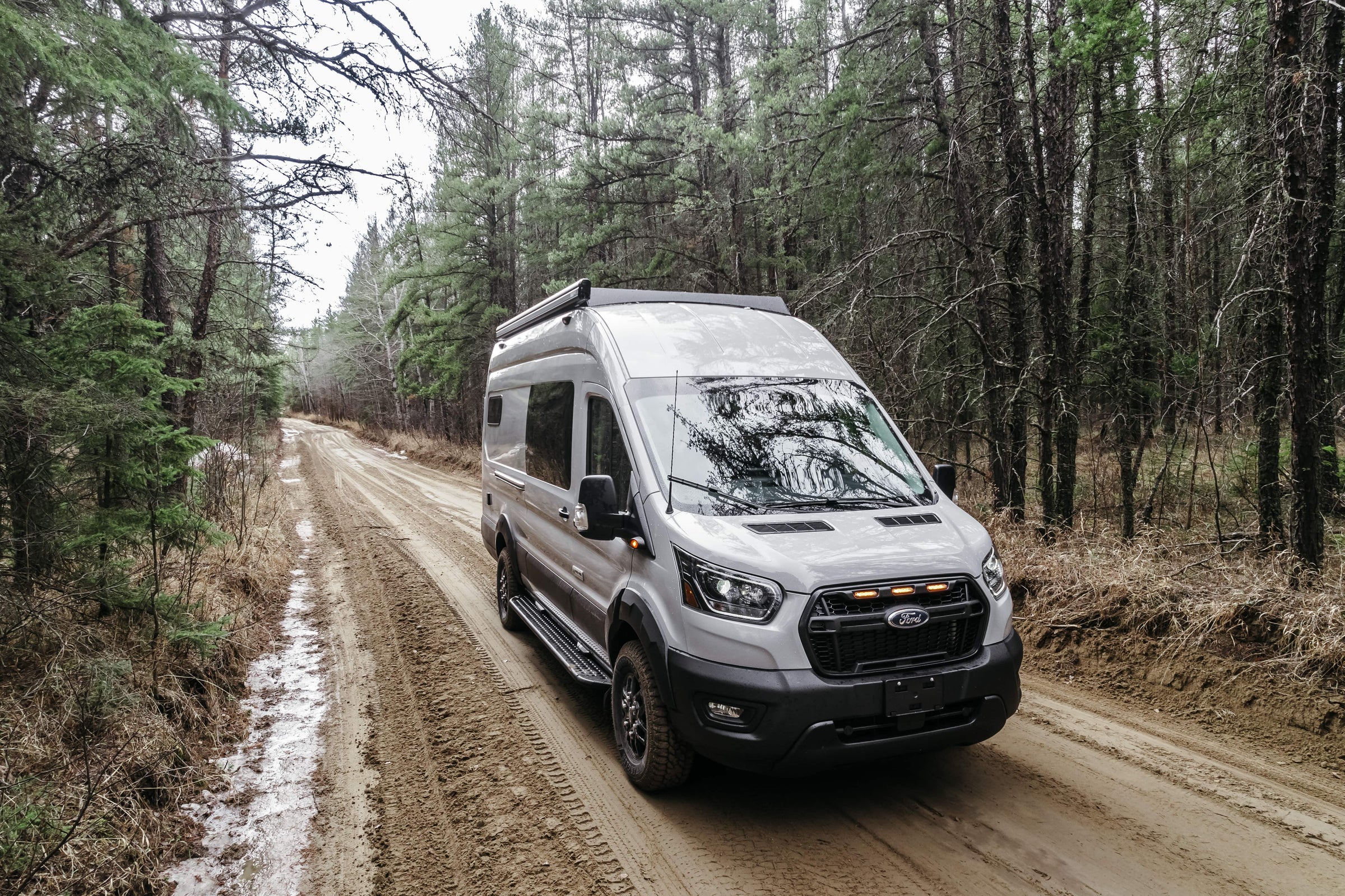 Ford transit trail van conversion on a dirt road in a forest
